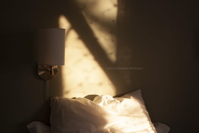 A photo of sunlight streaming into a bedroom, casting dappled shadows on the wall.