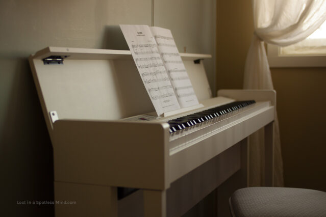 A photo of a white electrical piano, sheet music at the ready.